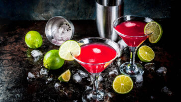 Red cosmopolitan cocktail with lime in martini glass, on dark rusty background
