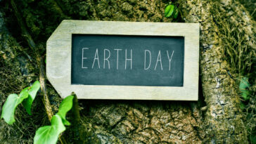 a chalkboard that says earth day against a tree