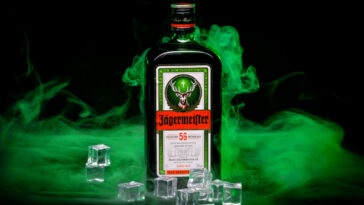 bottle of jagermeister with green smoke and ice cubes