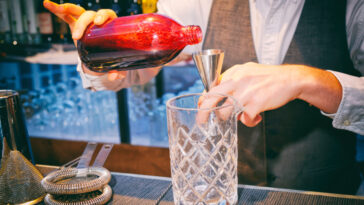 Bartender is pouring black currant shrub