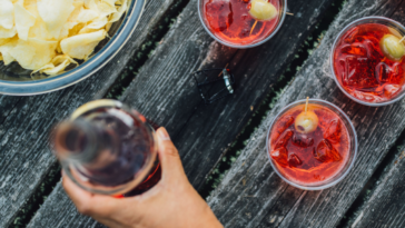 camping cocktails on picnic table with beer and bowl of chips