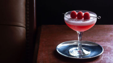 Clover Club Cocktail, a Sour Drink with Gin, Raspberries, and Egg White Foam in a Dark Luxurious Bar