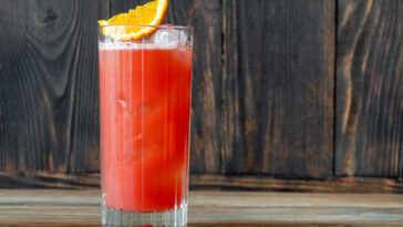 Glass of Garibaldi cocktail garnished with orange wedge