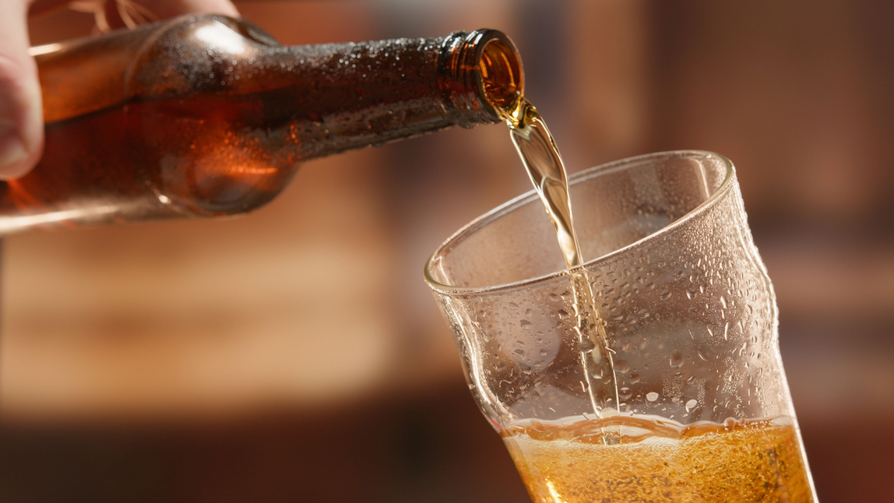 Lager beer foams and pours from bottle into glass.
