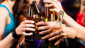 Group of party people - men and women - drinking beer