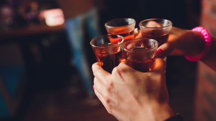 man holding four glass shot of best bourbon shots