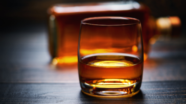 Wooden table with single shots of whiskey and full bottle