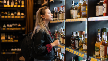 A modern woman wearing leather jacket and jeans buying alcohol