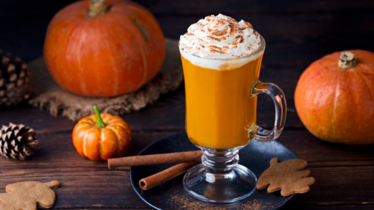pumpkin rum cocktail with whipped cream. Wooden background.