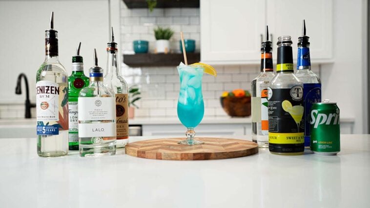 Adios Motherfucker cocktail with bottles of ingredients on the background