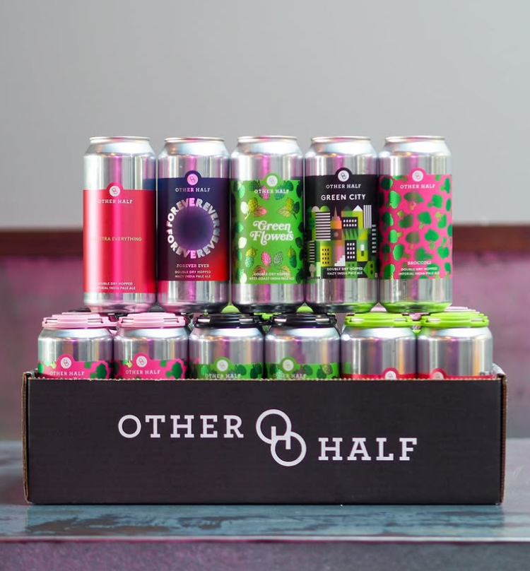 A colorful variety pack of Other Half Brewing Company beer cans, neatly arranged in a black branded box with vibrant and playful can designs on display.